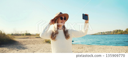 Travel, adventure, traveler woman taking selfie with phone on beach, girl using smartphone on coast Travel, adventure, traveler woman taking selfie with phone on beach, girl using smartphone on coast 135909770