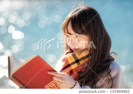A woman reading a book by the beach A woman reading a book by the beach 135909862