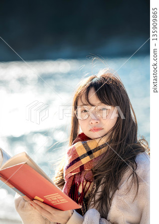 A woman reading a book by the beach A woman reading a book by the beach 135909865