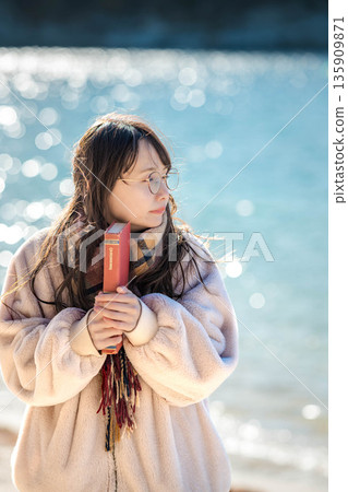 A woman reading a book by the beach 135909871