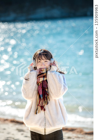 Young woman listening to music with headphones by the sea in winter 135909963