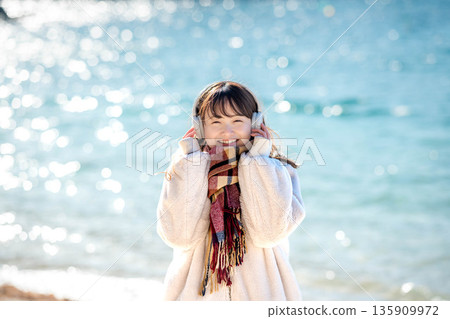 冬天，年輕女子在海邊戴著耳機聽音樂。 135909972