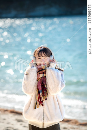 冬天，年輕女子在海邊戴著耳機聽音樂。 135909973