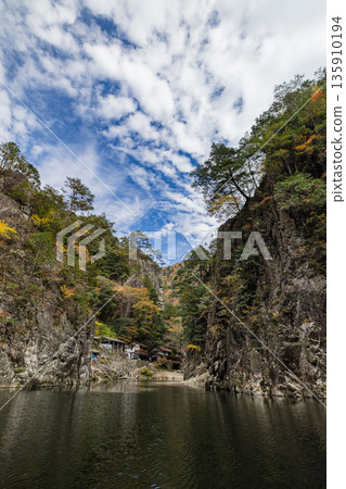 View of the rock cliffs and autumn foliage from the ferry at Kurofuchi in Sandankyo, a gorge in Akiota Town, Yamagata County, Hiroshima Prefecture, Japan View of the rock cliffs and autumn foliage from the ferry at Kurofuchi in Sandankyo, a gorge in Akiota Town, Yamagata County, Hiroshima Prefecture, Japan 135910194