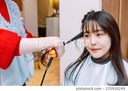 A young woman getting her hair done at a beauty salon A young woman getting her hair done at a beauty salon 135910249