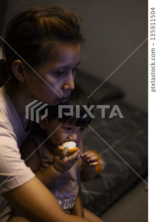 Overhead Shot Mom And Toddler Are Eating Santol, A warm photo of mom and toddler eating santol, juicy segments on small hands in soft kitchen light, for family snack or sweet bonding documentary. Overhead Shot Mom And Toddler Are Eating Santol, A warm photo of mom and toddler eating santol, juicy segments on small hands in soft kitchen light, for family snack or sweet bonding documentary. 135911504