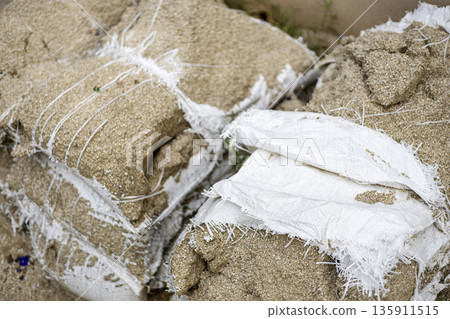 Worn Out Sandbag After Long Neglect, A gritty of worn out sandbag, frayed canvas splitting with sand spilling in harsh light, perfect for durability test or abandoned gear documentary. Worn Out Sandbag After Long Neglect, A gritty of worn out sandbag, frayed canvas splitting with sand spilling in harsh light, perfect for durability test or abandoned gear documentary. 135911515