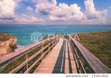 Wooden walkway on the rocky seashore. Photon viewpoint (Miradoiro de Foton) near Cathedrals Beach 135911602