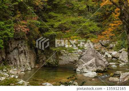 Rock walls and autumn foliage along the river at Sandankyo Gorge, a gorge in Akiota Town, Yamagata County, Hiroshima Prefecture, Japan Rock walls and autumn foliage along the river at Sandankyo Gorge, a gorge in Akiota Town, Yamagata County, Hiroshima Prefecture, Japan 135912165