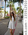 Happy woman in white dress enjoying sunny city street 135912910