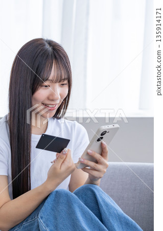 Young woman with smartphone and credit card 135914171