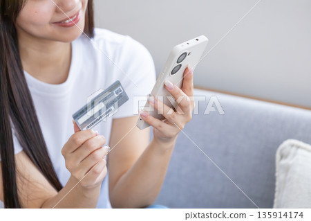 Young woman with smartphone and credit card 135914174
