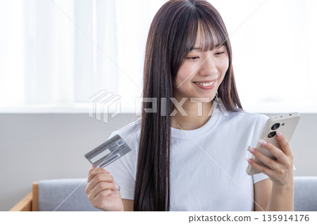 Young woman with smartphone and credit card 135914176
