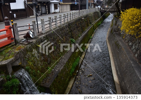 Old townscape of Takayama City, Gifu Prefecture, Japan. Old houses exuding a sense of history. Morning scene during the Takayama Spring Festival. A stream running through the city. Old townscape of Takayama City, Gifu Prefecture, Japan. Old houses exuding a sense of history. Morning scene during the Takayama Spring Festival. A stream running through the city. 135914373