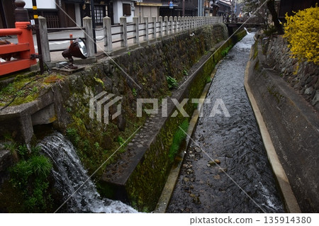 Old townscape of Takayama City, Gifu Prefecture, Japan. Old houses exuding a sense of history. Morning scene during the Takayama Spring Festival. A stream running through the city. Old townscape of Takayama City, Gifu Prefecture, Japan. Old houses exuding a sense of history. Morning scene during the Takayama Spring Festival. A stream running through the city. 135914380