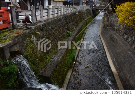 Old townscape of Takayama City, Gifu Prefecture, Japan. Old houses exuding a sense of history. Morning scene during the Takayama Spring Festival. A stream running through the city. Old townscape of Takayama City, Gifu Prefecture, Japan. Old houses exuding a sense of history. Morning scene during the Takayama Spring Festival. A stream running through the city. 135914381