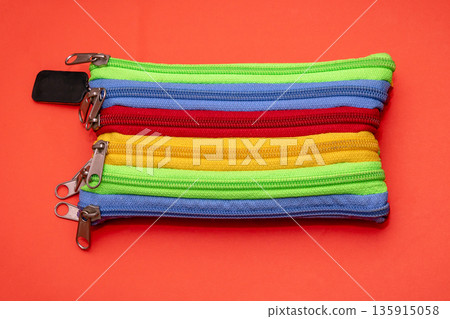 Multicoloured zipper pencil box on red background 135915058
