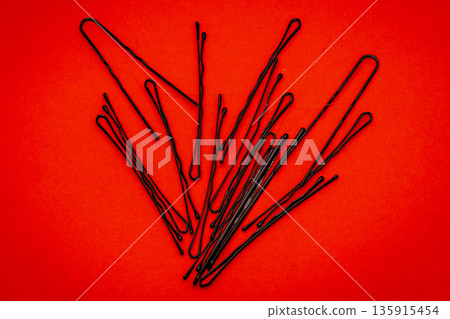 Metal bobby hair pins pile on red background Metal bobby hair pins pile on red background 135915454