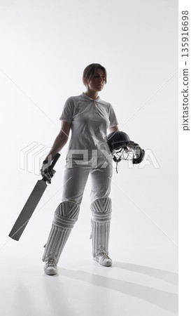 Female cricket batter standing ready with bat on white background. Female cricket batter standing ready with bat on white background. 135916698