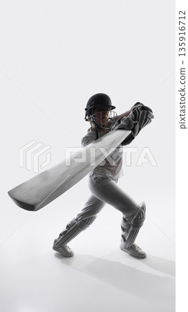 Female cricket player hitting ball with bat in studio. Female cricket player hitting ball with bat in studio. 135916712