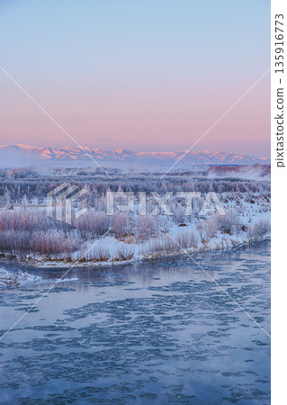 The Hidaka Mountains dyed in a pale pink sky and the frozen Tokachi River 135916773