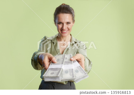 Offering wealth: Woman smiles with stacks of dollars 135916813
