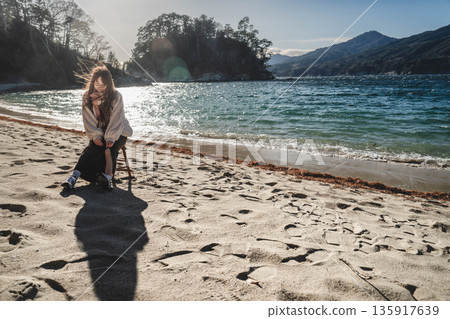 一位年輕女子坐在海灘的椅子上 135917639