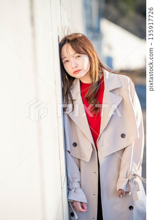 Portrait of a young woman leaning against a wall Portrait of a young woman leaning against a wall 135917726
