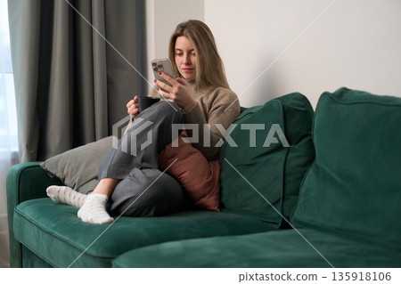 Quiet Afternoon Browsing Her Phone on a Green Sofa Quiet Afternoon Browsing Her Phone on a Green Sofa 135918106