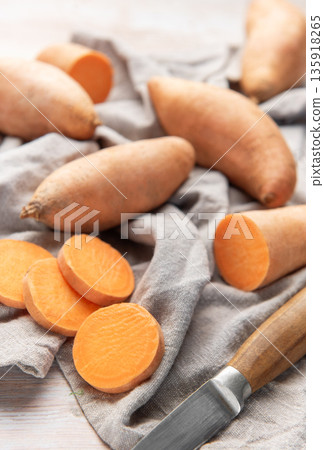 Raw sweet potatoes on linen cloth with knife Raw sweet potatoes on linen cloth with knife 135918265