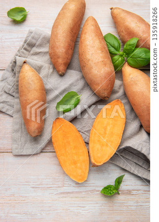 Fresh sweet potatoes and basil on wooden background 135918266
