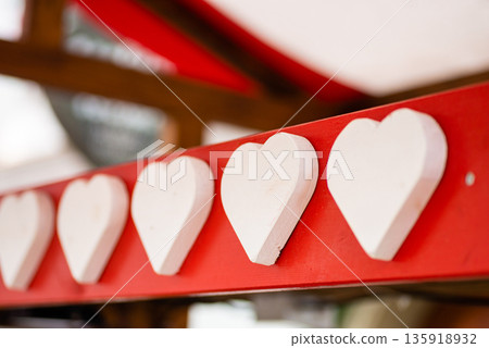 Festive white heart decorations aligned on red ribbon creating romantic celebration background 135918932