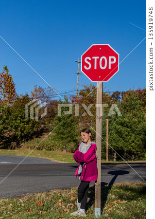A girl stands in front of a stop sign A girl stands in front of a stop sign 135919748