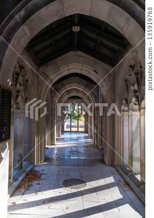 A long, narrow hallway with arched windows and a plaque on the wall 135919768