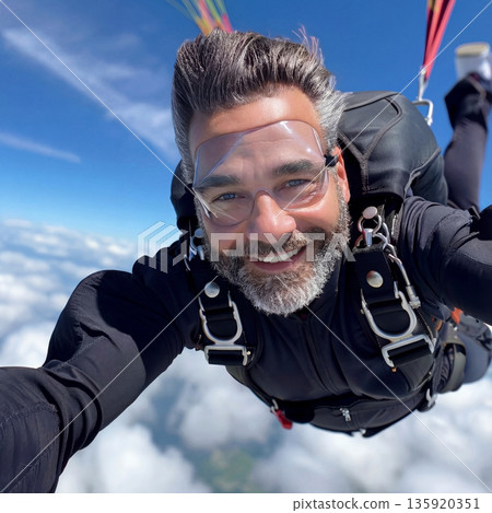 Man skydiving with a parachute high above the clouds 135920351