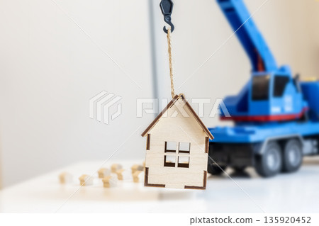 Small figure of house with lifting truck crane. Removal service. Construction of houses. 135920452