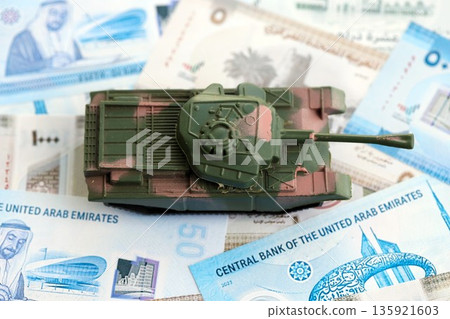 United Arab Emirates dirham currency money bills and toy tank close up. The concept of army funds and weapons sales United Arab Emirates dirham currency money bills and toy tank close up. The concept of army funds and weapons sales 135921603