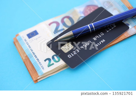 Credit card and pen with euro currency money bills banknotes on light blue background. Business, financial operations and accounting in European Union Credit card and pen with euro currency money bills banknotes on light blue background. Business, financial operations and accounting in European Union 135921701