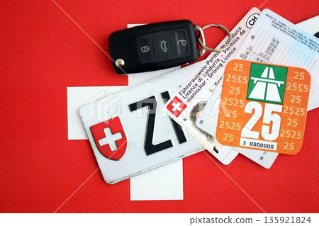 Switzerland vignette sticker for 2025 year and license plate with ignition key on Swiss flag close up. Driving permit and registration concept Switzerland vignette sticker for 2025 year and license plate with ignition key on Swiss flag close up. Driving permit and registration concept 135921824
