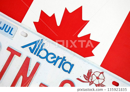 Alberta canadian car license plate on flag of Canada close up. Driving permit and registration concept 135921835