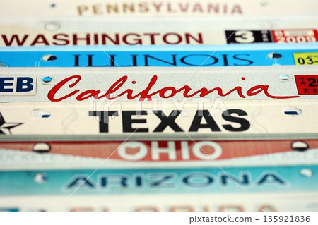 Old US car license plates with various state names. Concept of driving in United States. Reaching a car registration 135921836