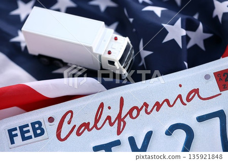 Toy truck and USA state of California license plate on US flag. Concept of driving in California. Reaching a driving permit Toy truck and USA state of California license plate on US flag. Concept of driving in California. Reaching a driving permit 135921848