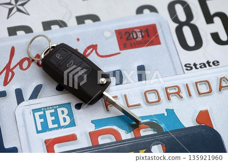 Remote control car keys on US license plates with state names close up. Concept of driving in United States. Reaching a car registration 135921960