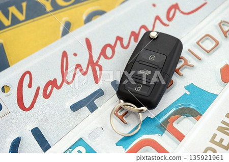 Remote control car keys on US license plates with various state names close up. Concept of driving in United States. Reaching a car registration 135921961