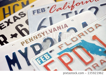 Old US car license plates with various state names close up. Concept of driving in United States. Reaching a car registration 135921962