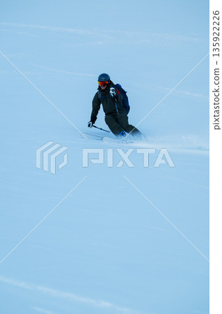 Skier carving through powder on a blue winter day, off-piste adventure in fresh snow 135922226