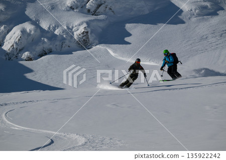 Two Skiers Descend a Snowy Alpine Slope in Off-Piste Freeride Adventure 135922242
