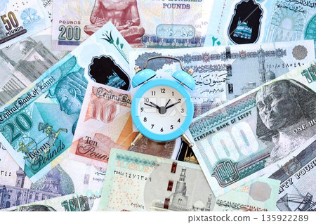 Egyptian pound currency money bills and alarm clock close up. The concept of time management and income Egyptian pound currency money bills and alarm clock close up. The concept of time management and income 135922289