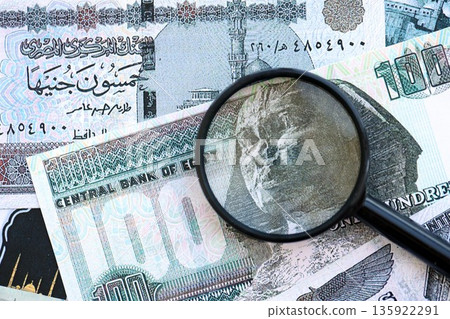 Egyptian pound currency money bills and magnifying glass close up. The concept of financial monitoring and taxation Egyptian pound currency money bills and magnifying glass close up. The concept of financial monitoring and taxation 135922291