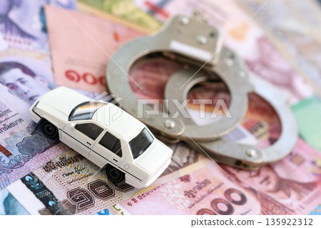 Thai baht currency money bills and toy car with handcuffs close up. The concept of car accident 135922312